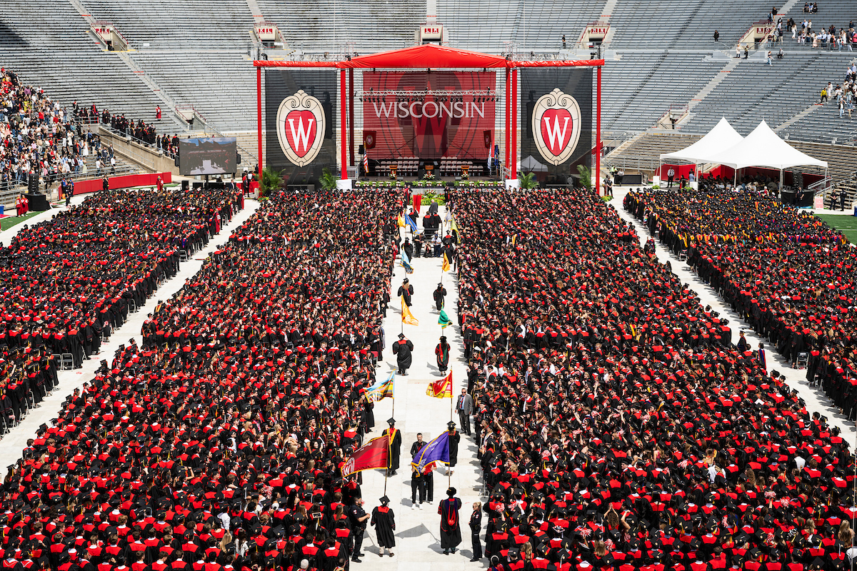Top-down view of the UW commencement stage with a sea of students in red and black.
